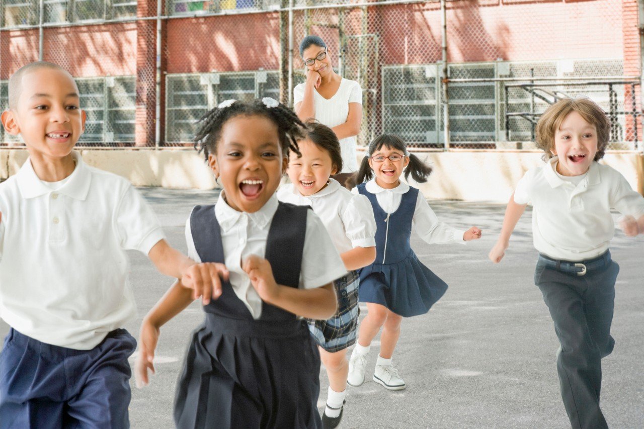 Elementary school children run in a playground during break